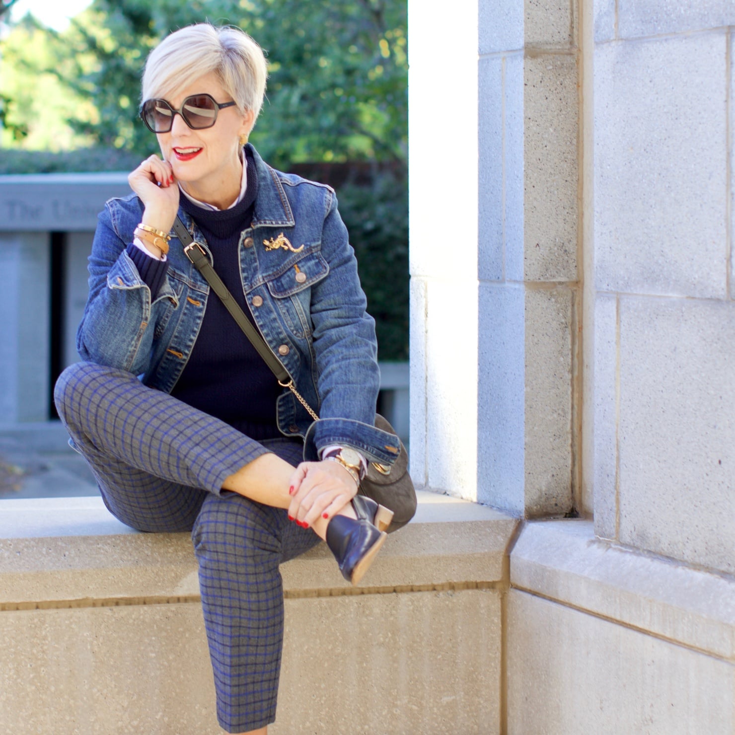 beth from style at a certain age wears a jean jacket, plaid pants, navy blue roll neck sweater, striped shirt, and navy blue loafers