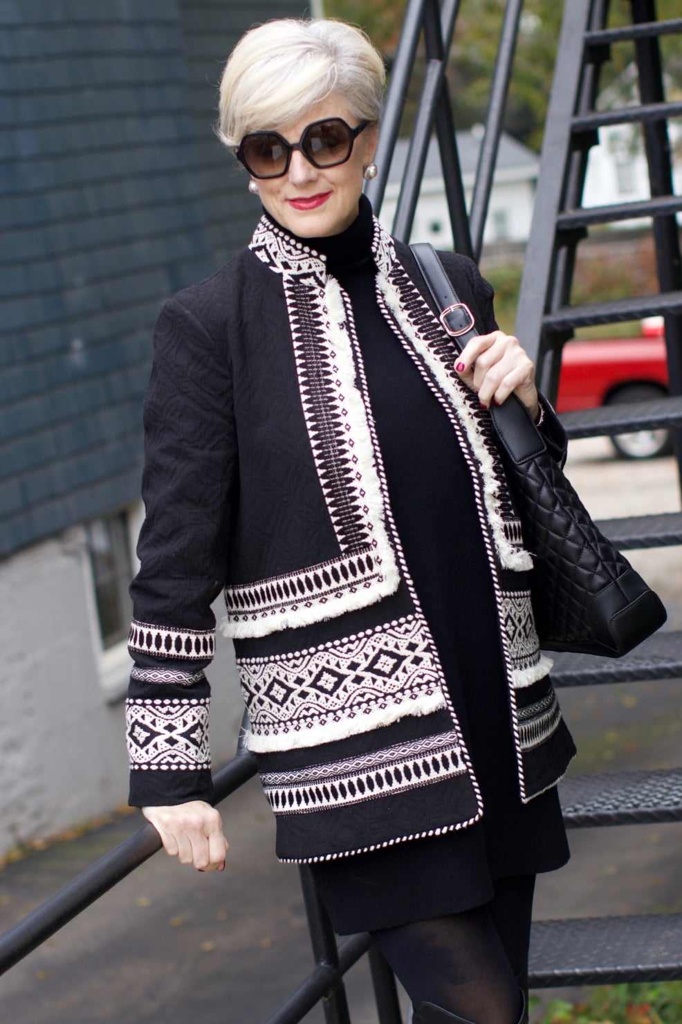 beth from style at a certain age wears a cashmere sweater dress from everlane, anthropologie embroidered jacket, black over the knee boots