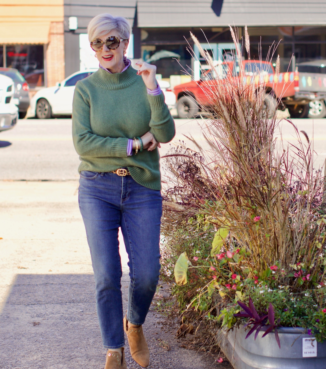 beth from Style at a Certain Age wears a chunky turtleneck layered over a stripe button down, skinny ankle jeans, a denim jacket, and booties