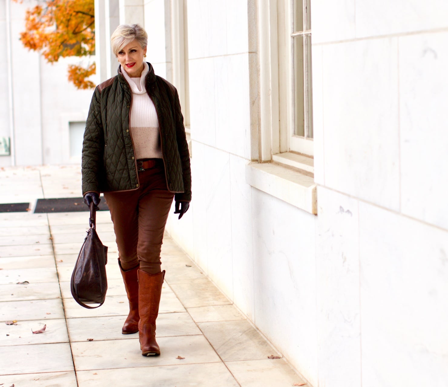 beth from Style at a Certain Age is wearing Ralph Lauren faux leather pants, chunky cashmere sweater, green utility jacket, Frye boots, and Frye hobo handbag