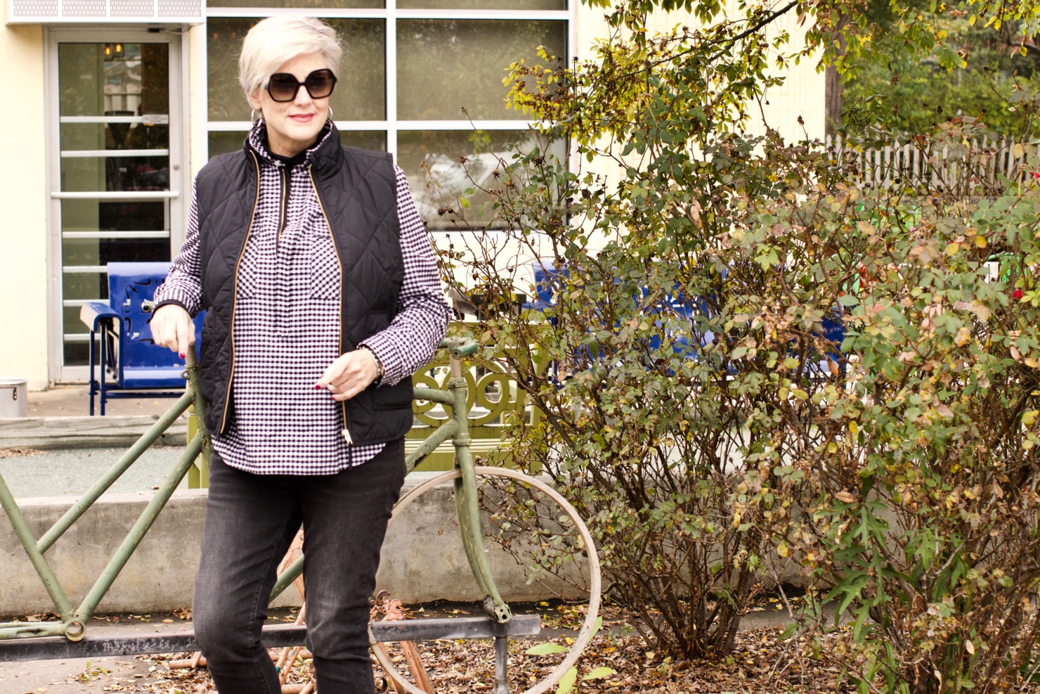 beth from style at a certain age wears high rise skinny jeans, tissue turtleneck, gingham shirt jacket, and puffer vest