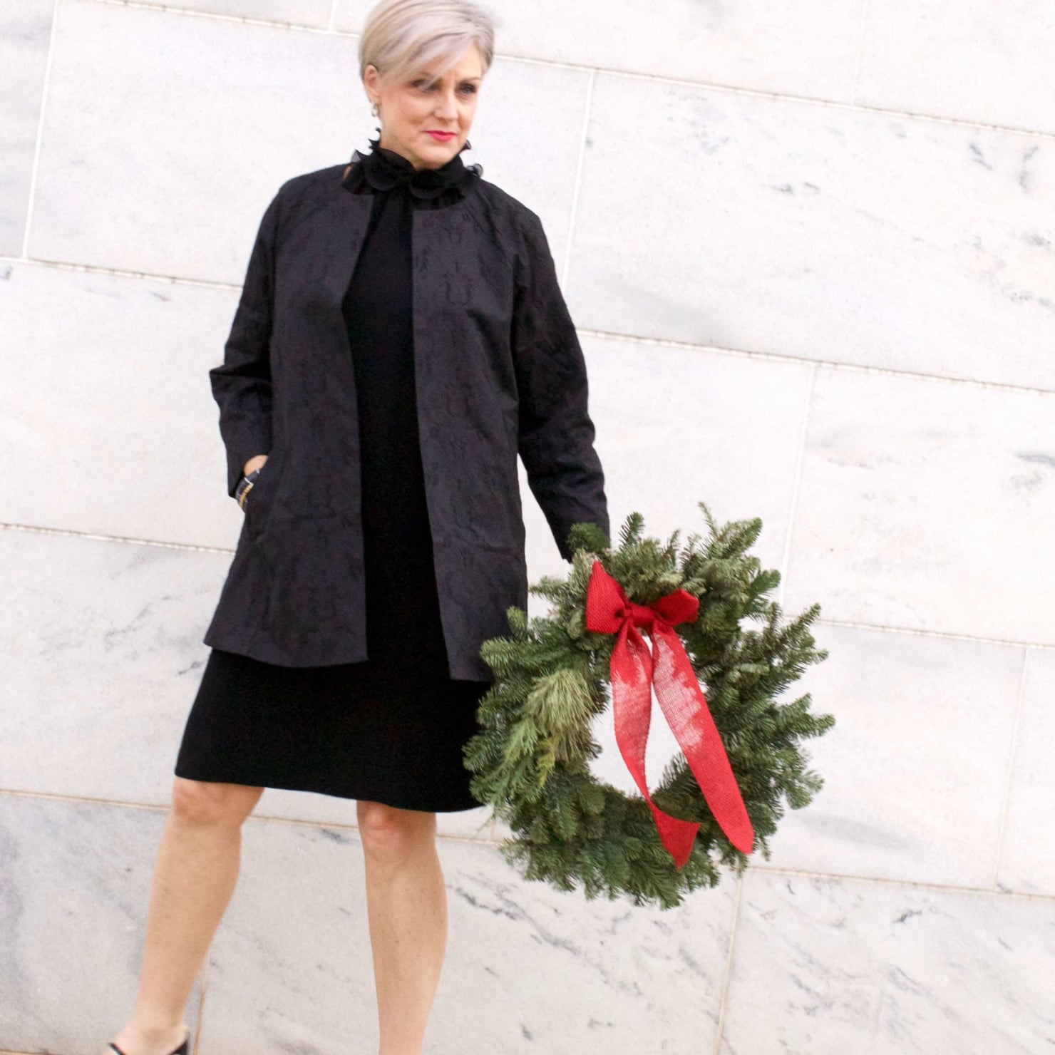 beth from Style at a Certain Age wears a Eileen Fisher shimmer jacquard 3/4 sleeve jacket and ruffled black dress