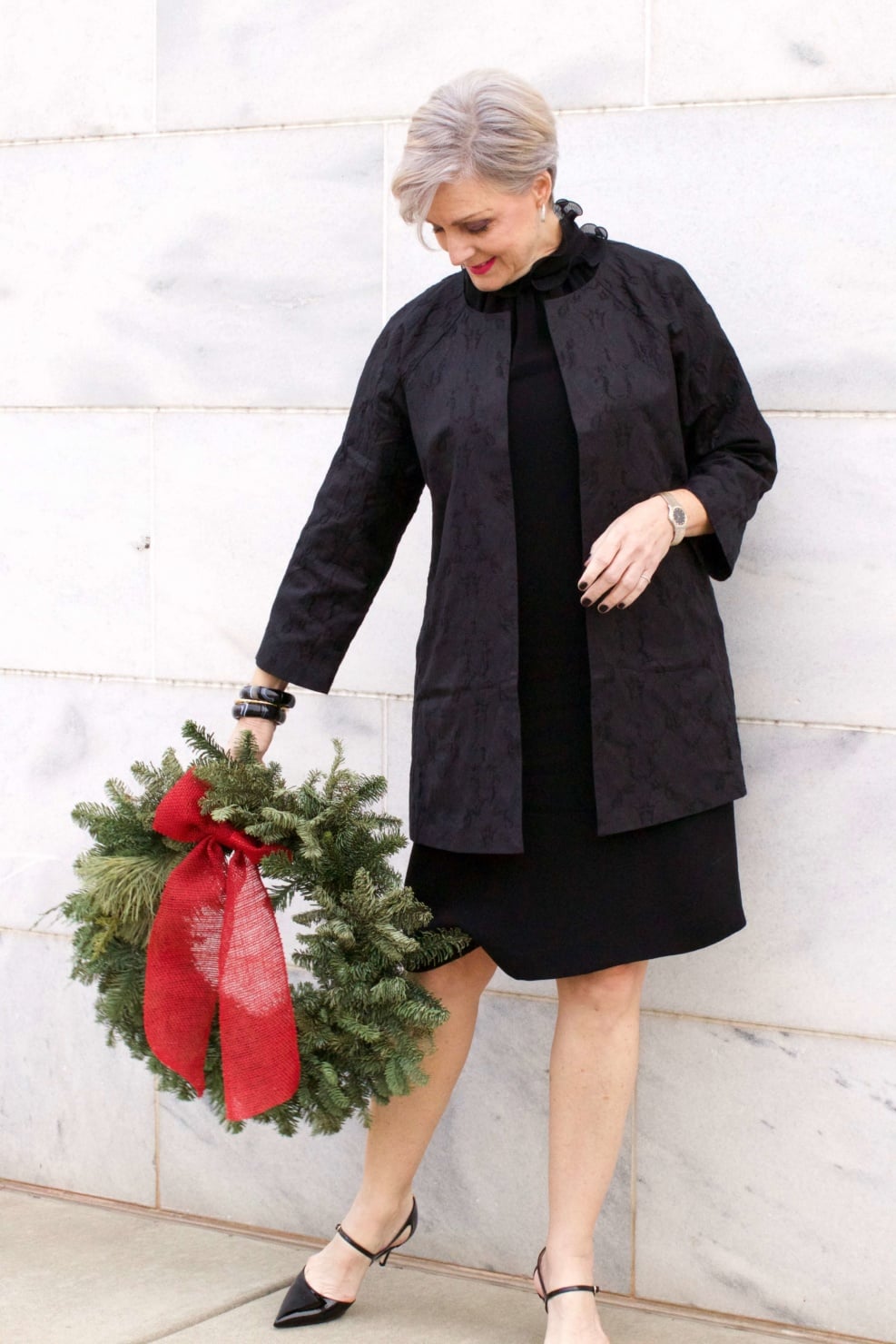 beth from Style at a Certain Age wears a Eileen Fisher shimmer jacquard 3/4 sleeve jacket and ruffled black dress 