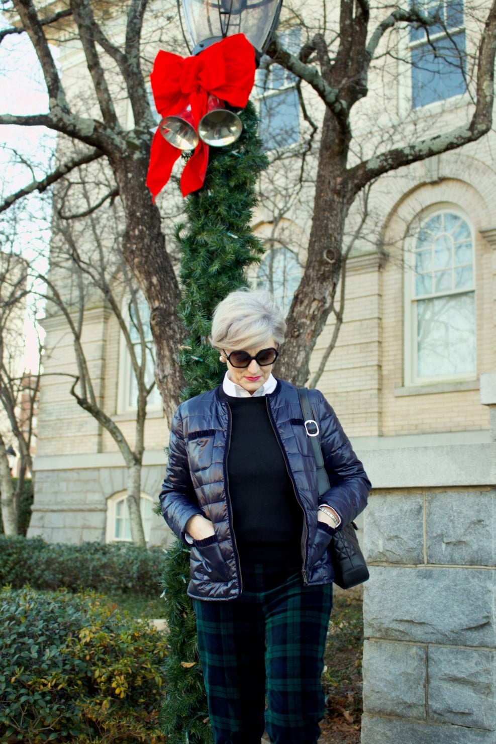 beth from Style at a Certain Age wears a navy puffer jacket, black cashmere crewneck and black watch plaid ankle pants