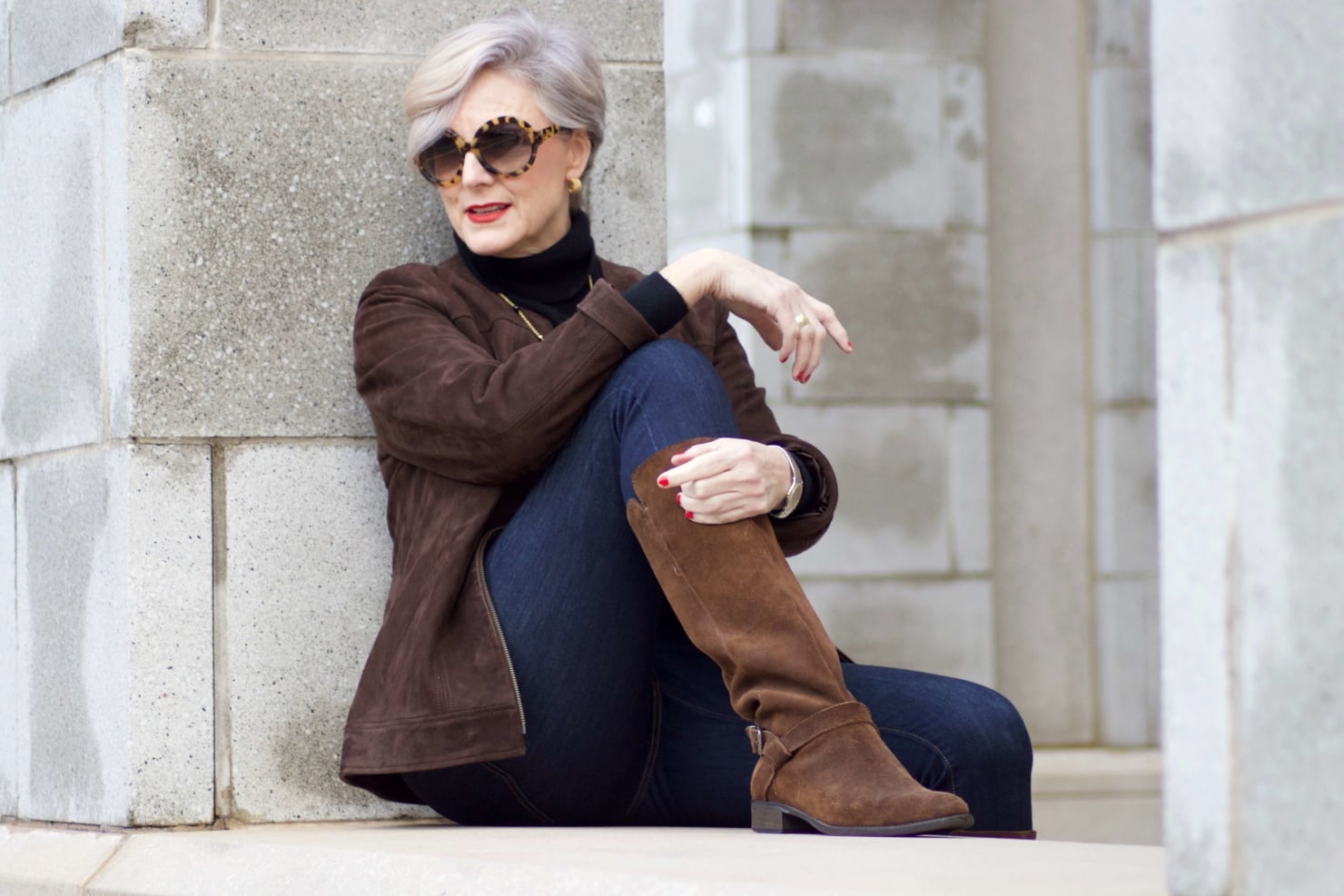 beth from Style at a Certain Age wears a black turtleneck, brown suede jacket, dark rinse denim and suede riding boots