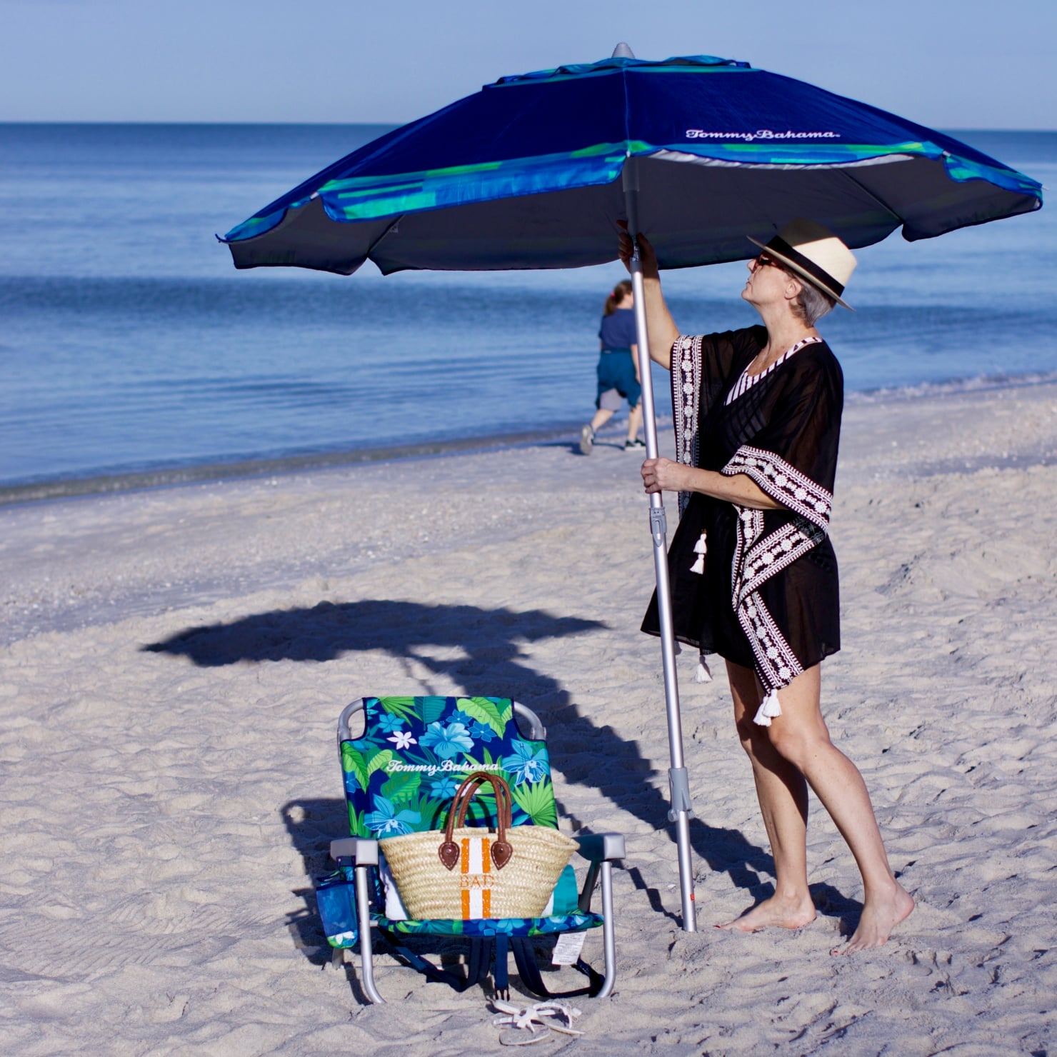 beth from Style at a Certain Age wears beach essentials, Ralph Lauren striped one-piece swimsuit, Tory Burch cover-up, jelly flip-flops, panama hat, and straw tote