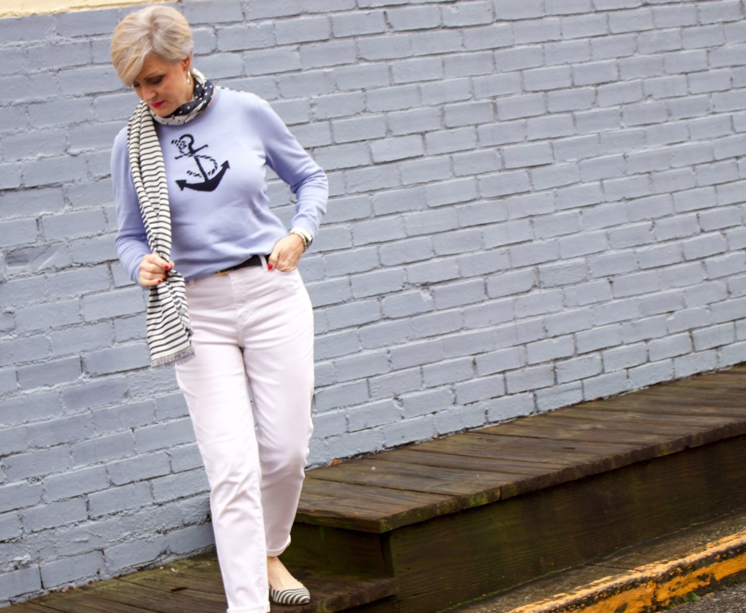 beth from Style at a Certain Age wears a yellow slicker from Talbots, white denim, anchor sweater, polka dot and striped scarf, and striped flats