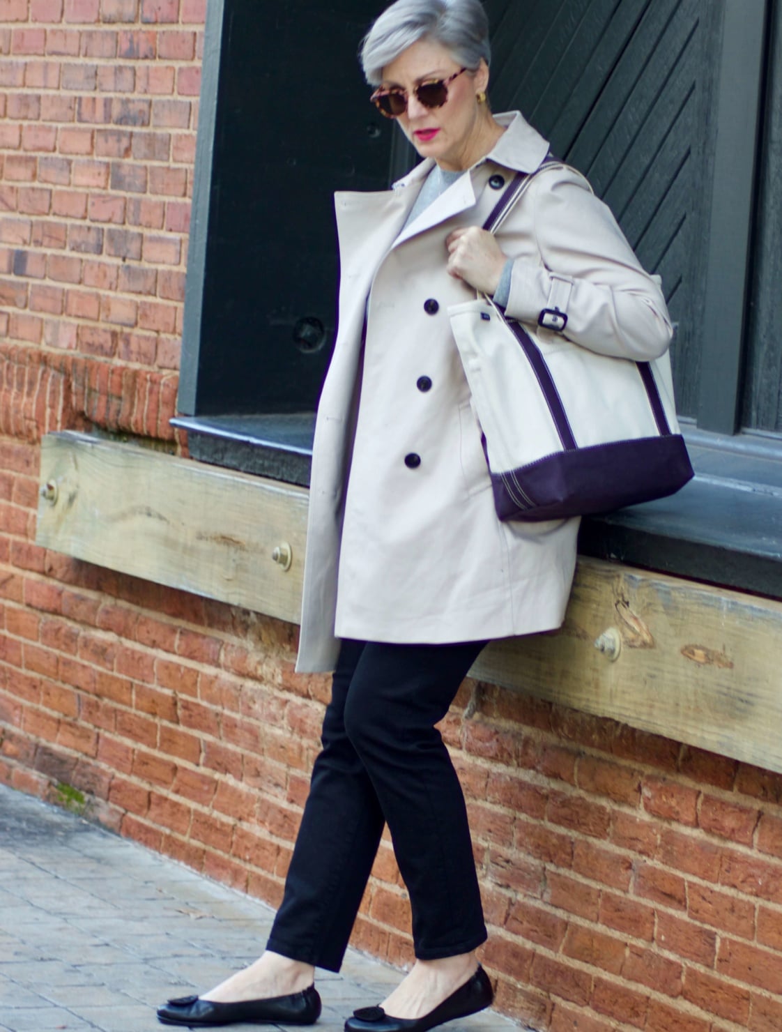 beth from Style at a Certain Age wears an Everlane grey cashmere crewneck, high rise black cigarette jean, Tory Burch black ballet flats and a double-breasted trench coat