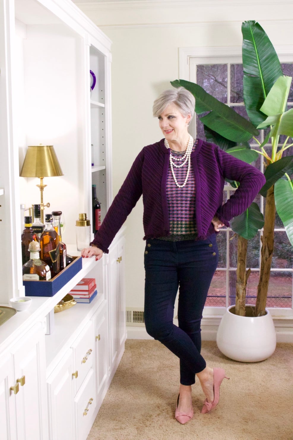 beth from Style at a Certain Age wears a fringed cardigan sweater, denim, and pink suede pumps