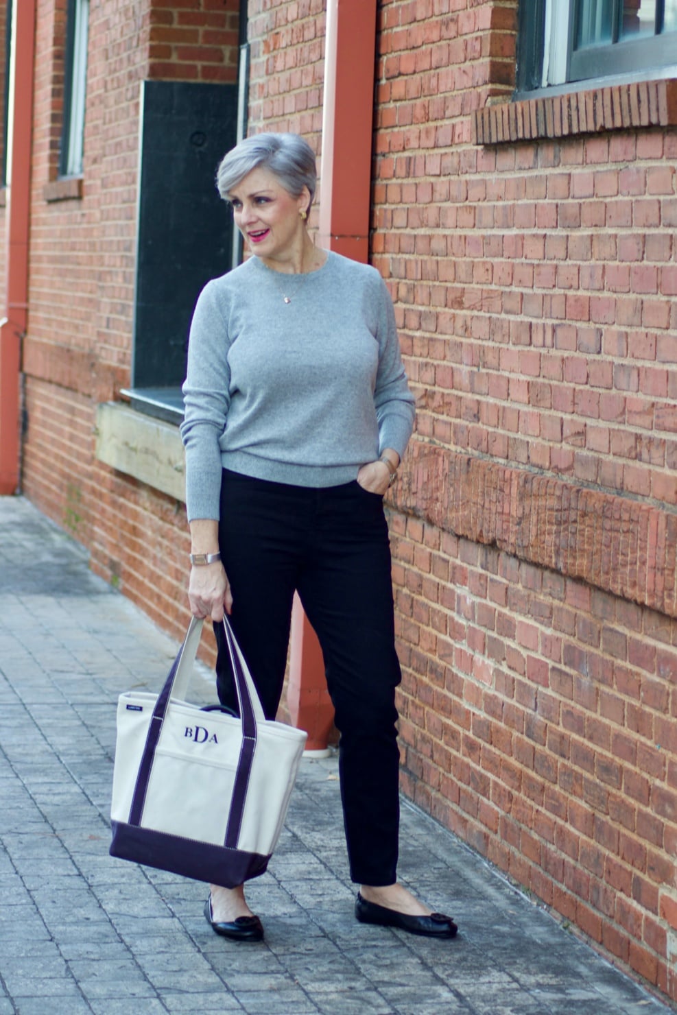 beth from Style at a Certain Age wears an Everlane grey cashmere crewneck, high rise black cigarette jean, Tory Burch black ballet flats and a double-breasted trench coat