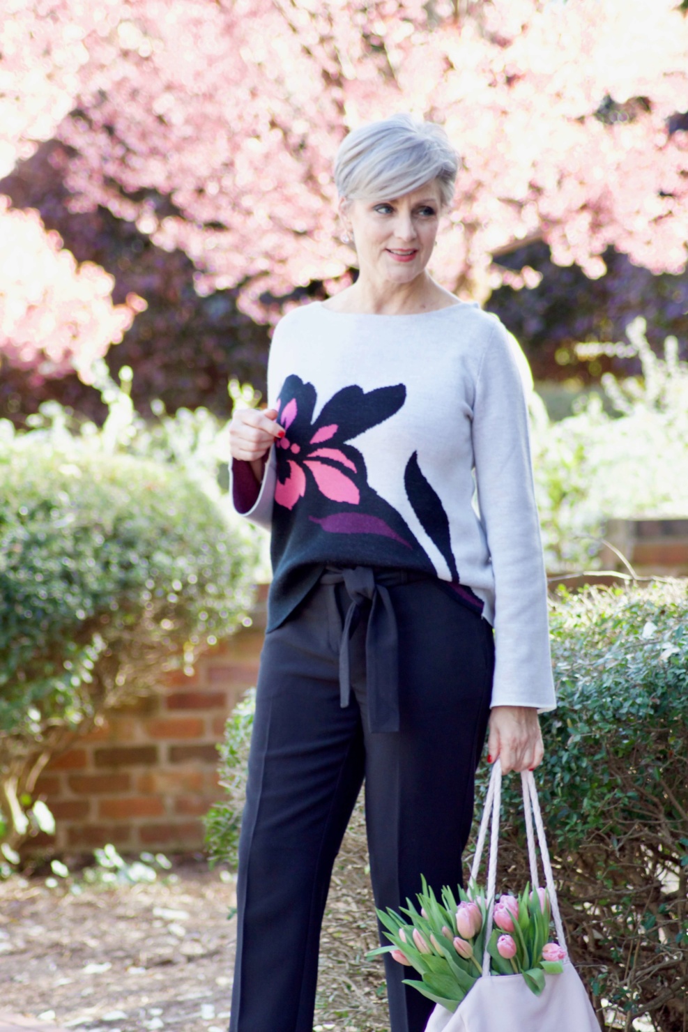 beth from Style at a Certain Age wears an Ann Taylor floral sweater, black ankle tie pants, and pink kitten heels