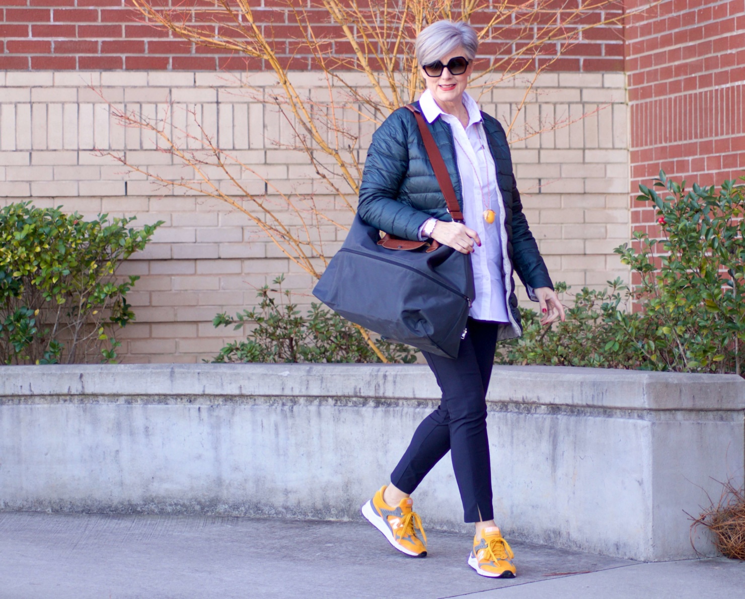 beth from Style at a Certain Age wears Athleta pants, white shirt, puffer jacket, and sneakers