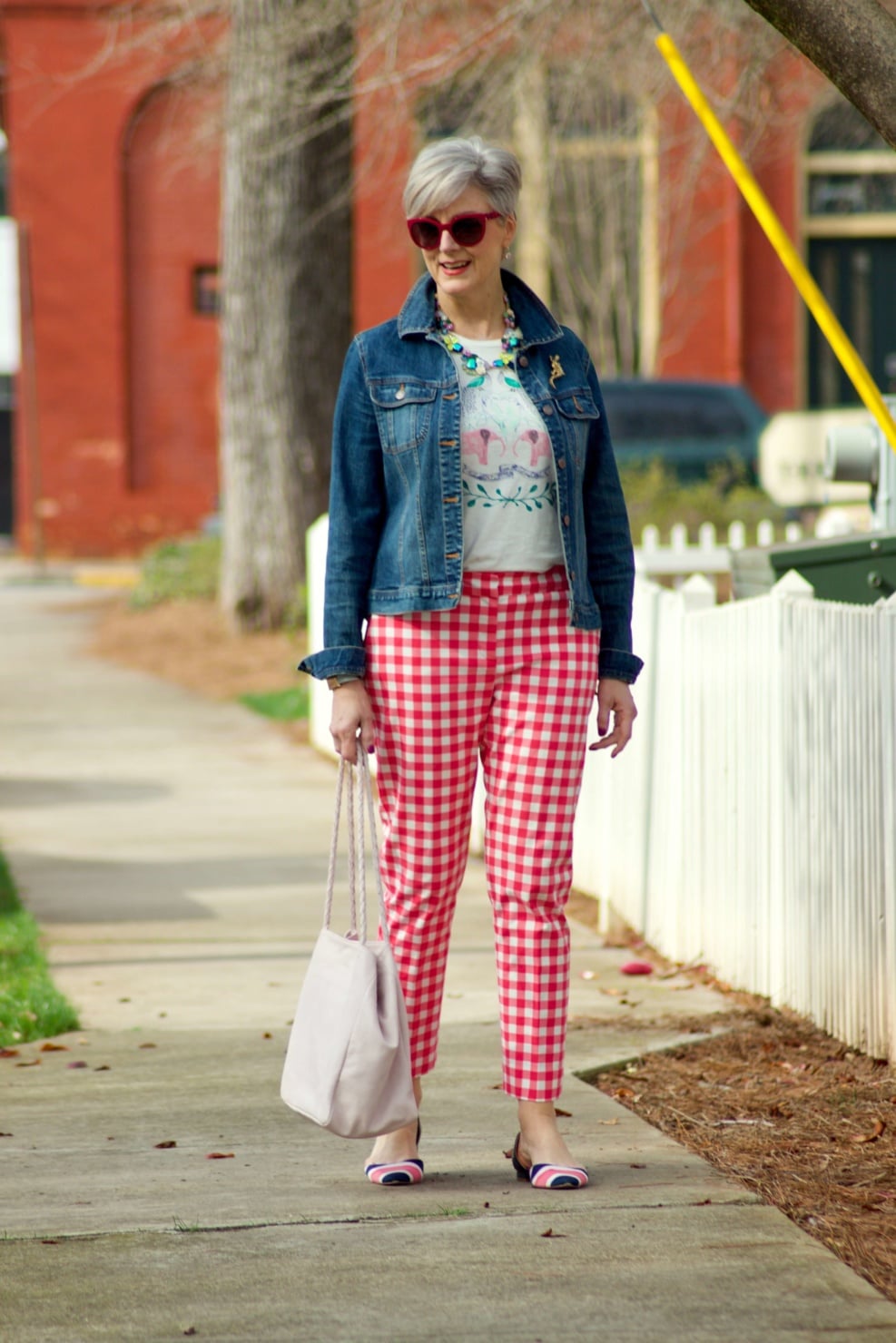 beth from Style at a Certain Age wears pink gingham pants, graphic tee, and denim jacket