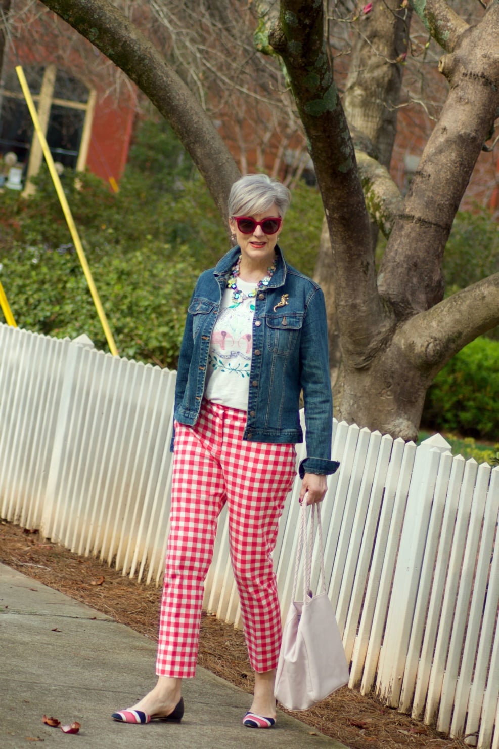beth from Style at a Certain Age wears pink gingham pants, graphic tee, and denim jacket