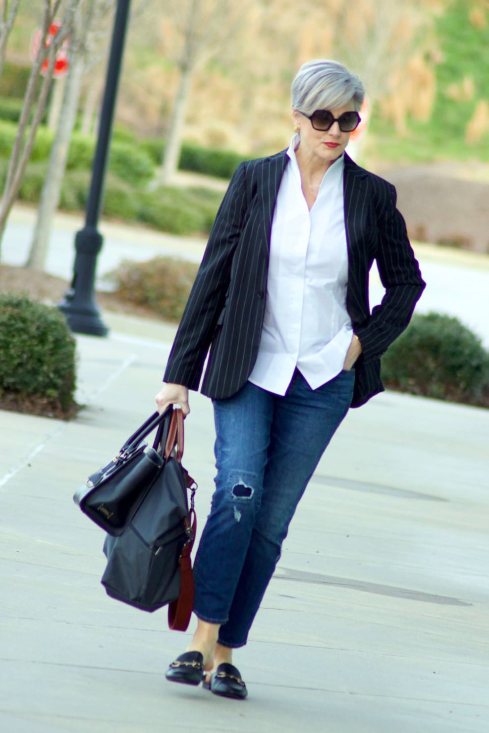 beth from Style at a Certain Age travels in style in a pinstripe blazer, white button down, blue jeans, and black slides