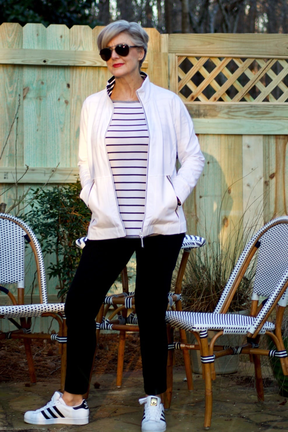 beth from Style at a Certain Age wears a stripe t-shirt, black yoga pants, and white track jacket