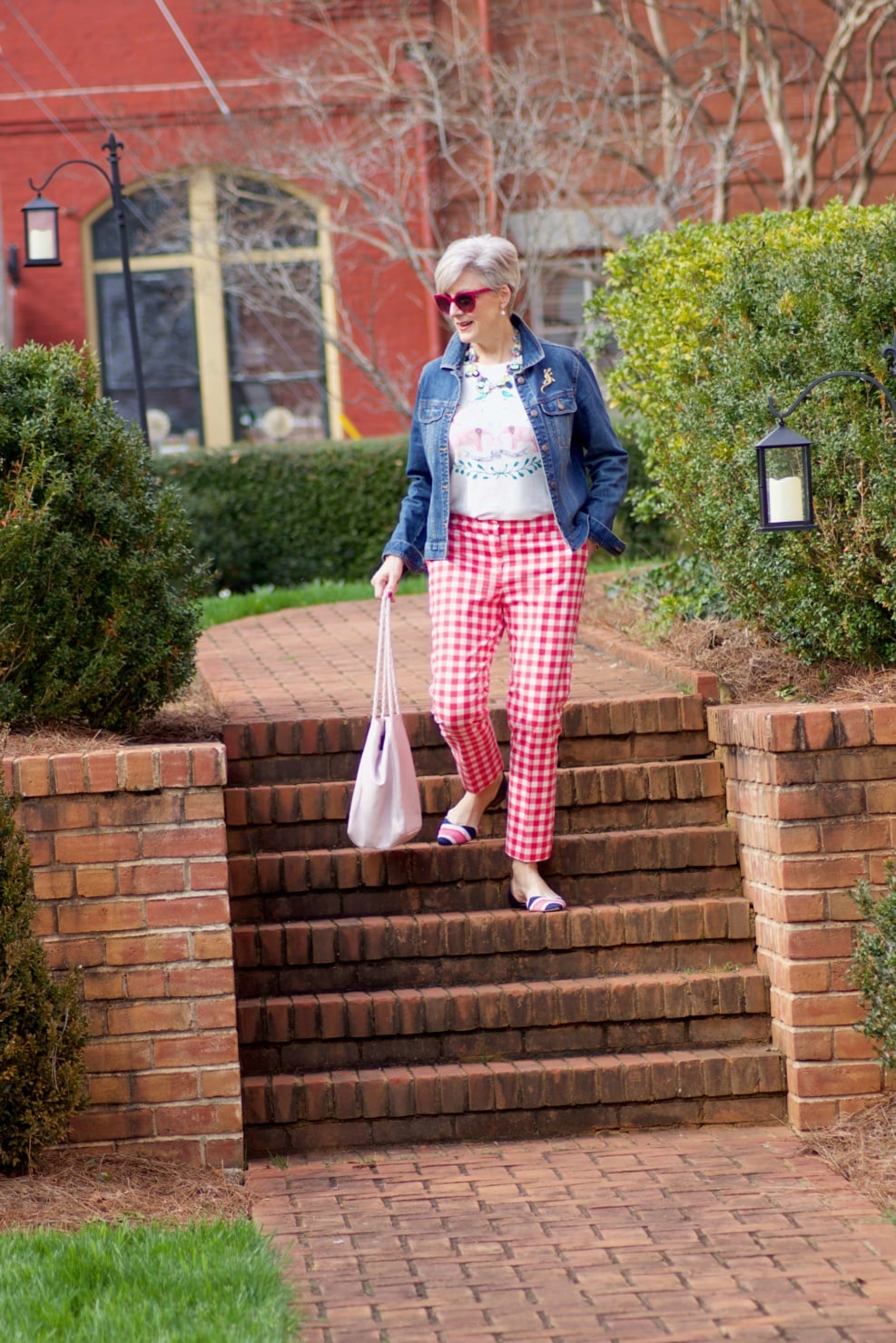 beth from Style at a Certain Age wears pink gingham pants, graphic tee, and denim jacket