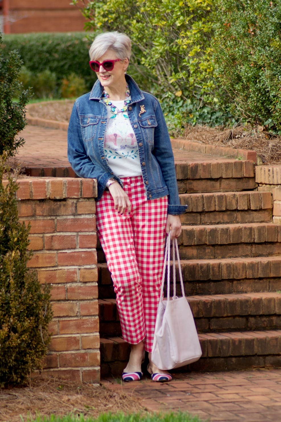 beth from Style at a Certain Age wears pink gingham pants, graphic tee, and denim jacket