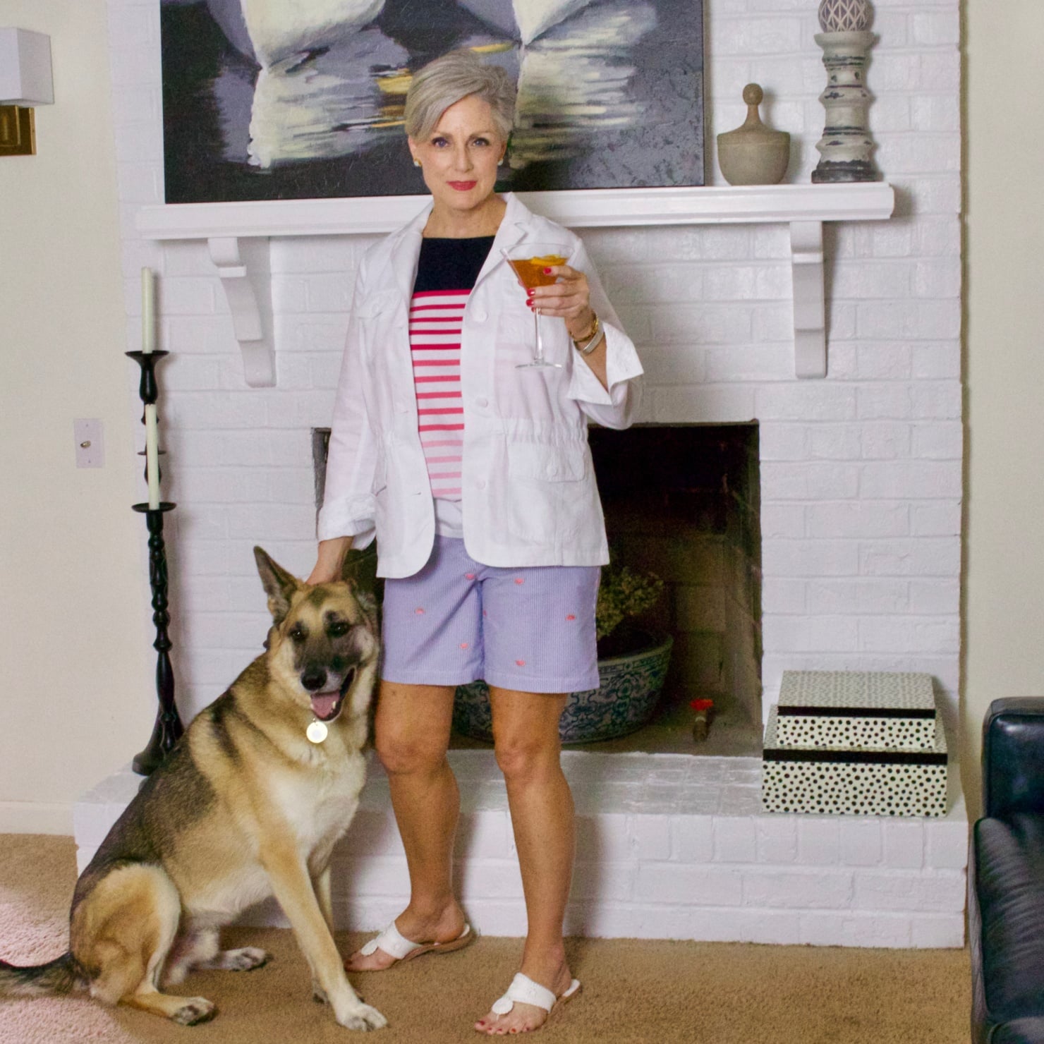 beth from Style at a Certain Age wears watermelon print shorts, striped tee, white jacket and jack rodgers sandals