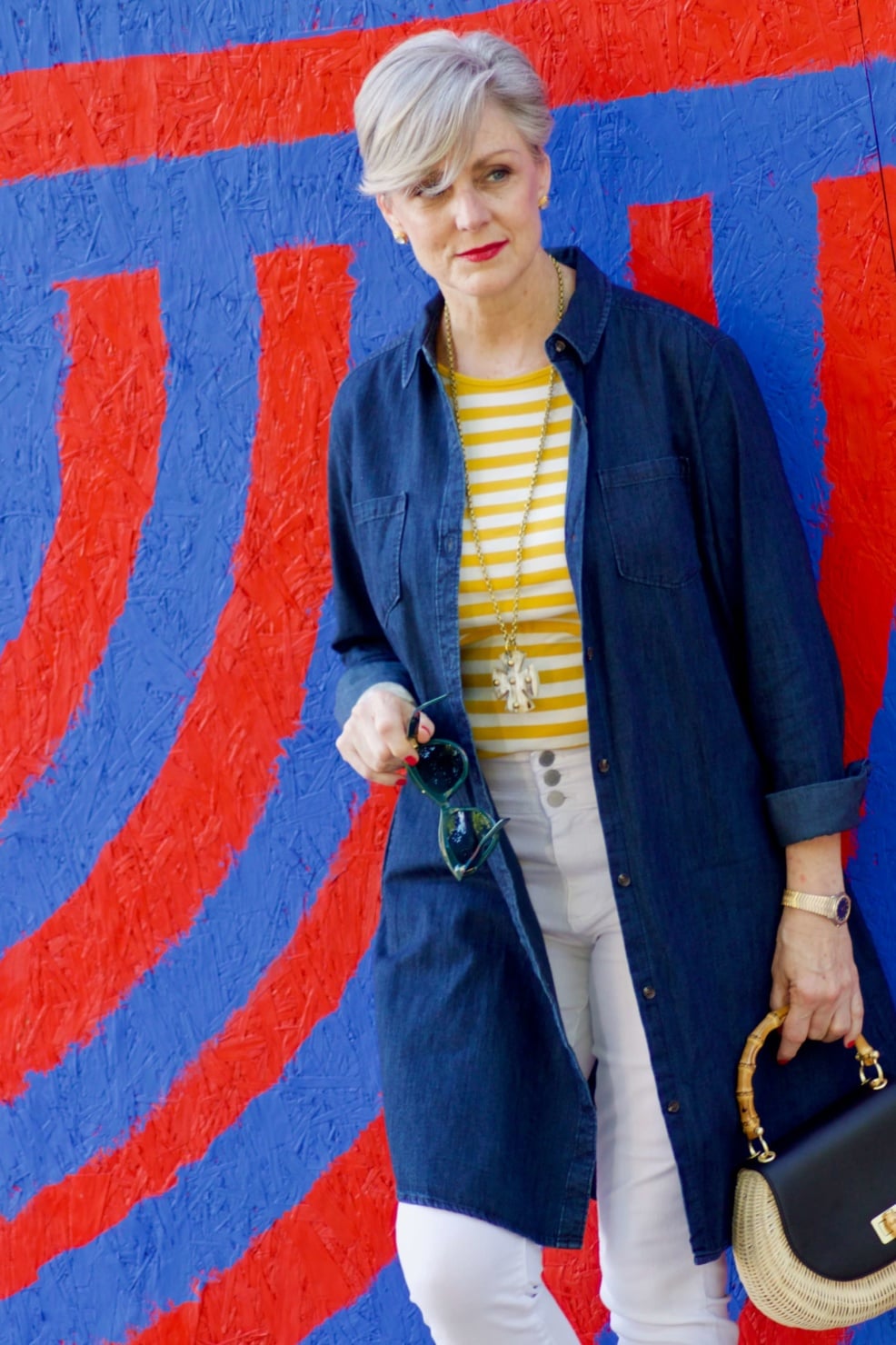 beth from Style at a Certain Age wears a denim duster, striped tee, white denim, suede sandals and wicker handbag