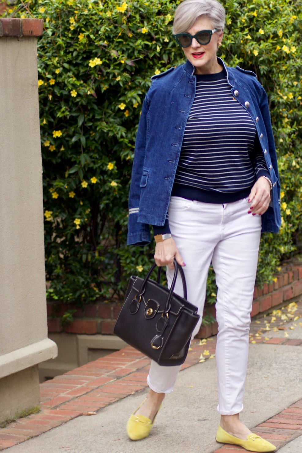 beth from Style at a Certain Age wears a denim military jacket, striped sweater, and white denim