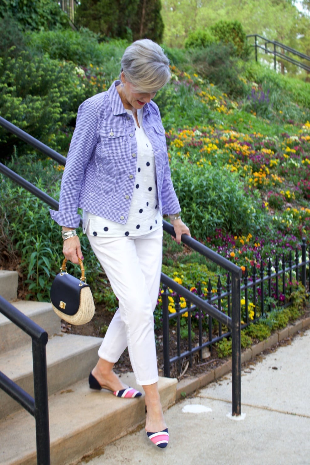 beth from Style at a Certain Age wears a gingham jean jacket, polka dot top, white chinos and wicker handbag