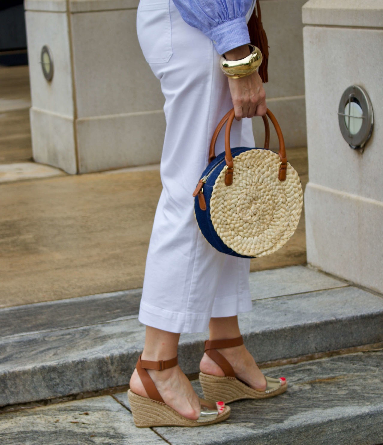 cropped white denim, striped linen shirt, cornhusk handbag, and wedge sandals