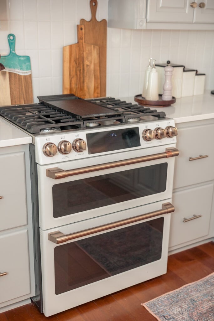 White dual oven gas range with brass accents and wood cutting boards — timeless 2025 kitchen remodel upgrade.