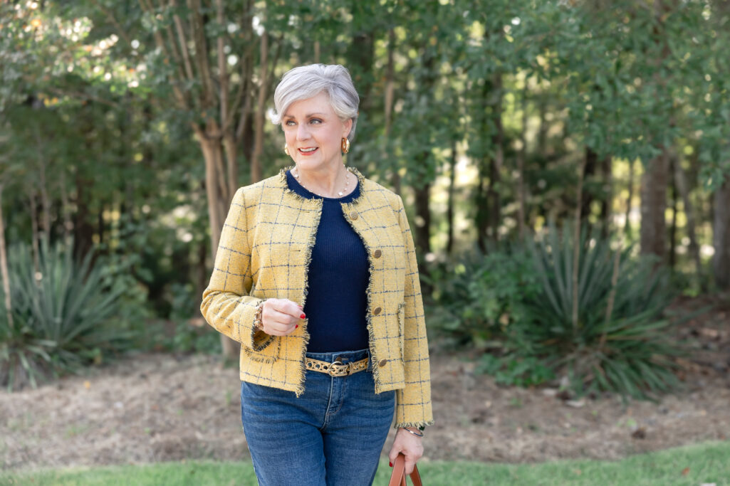 Elegant over-50 fall outfit idea with a yellow tweed blazer, navy top, straight-leg jeans, and metallic flats. Golden Moments Golden Bachelor