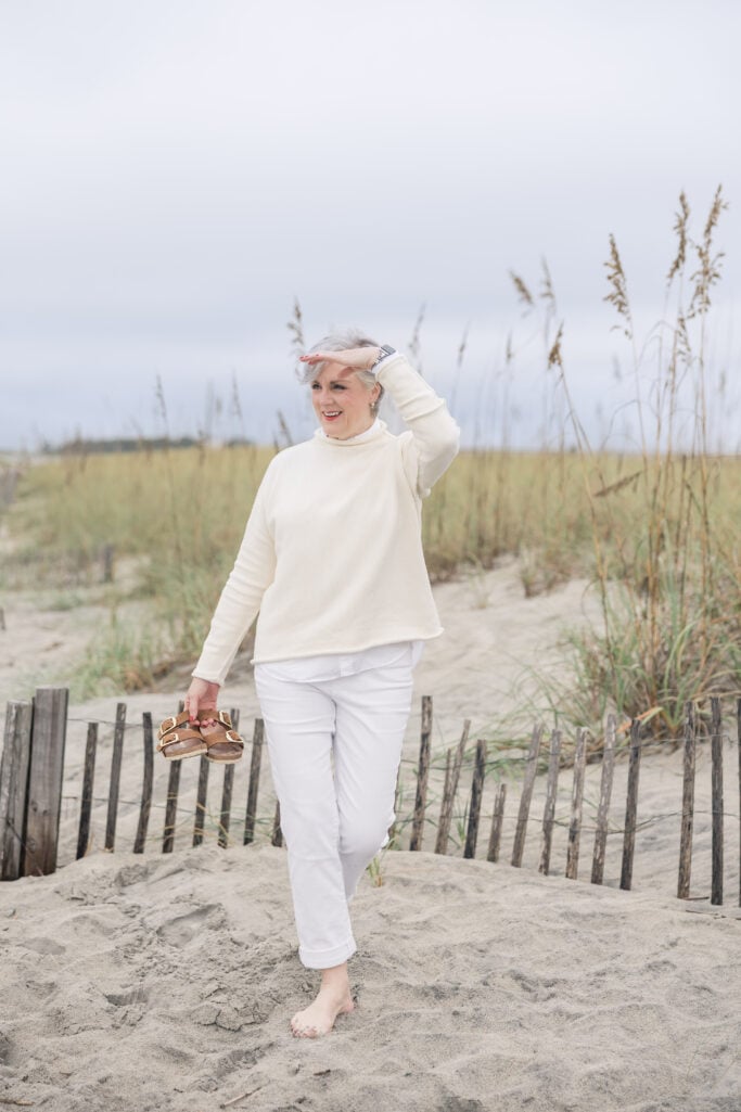 Beth Djalali in ivory sweater and white jeans on the beach—cozy monochrome fall fashion idea.