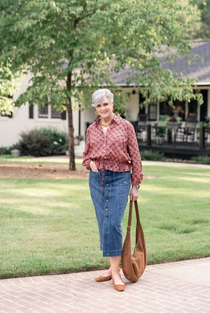 Woman wearing a dark denim midi skirt with a feminine floral top.