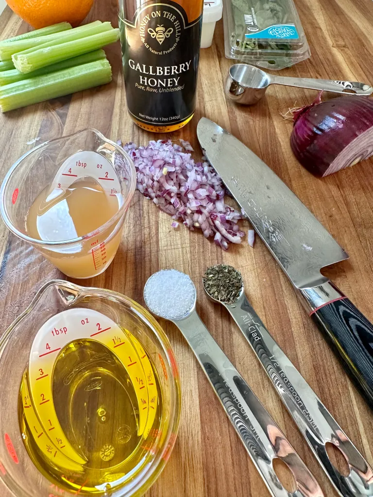 Vinaigrette ingredients on cutting board with olive oil apple cider vinegar honey and fresh mint - Mediterranean salad dressing