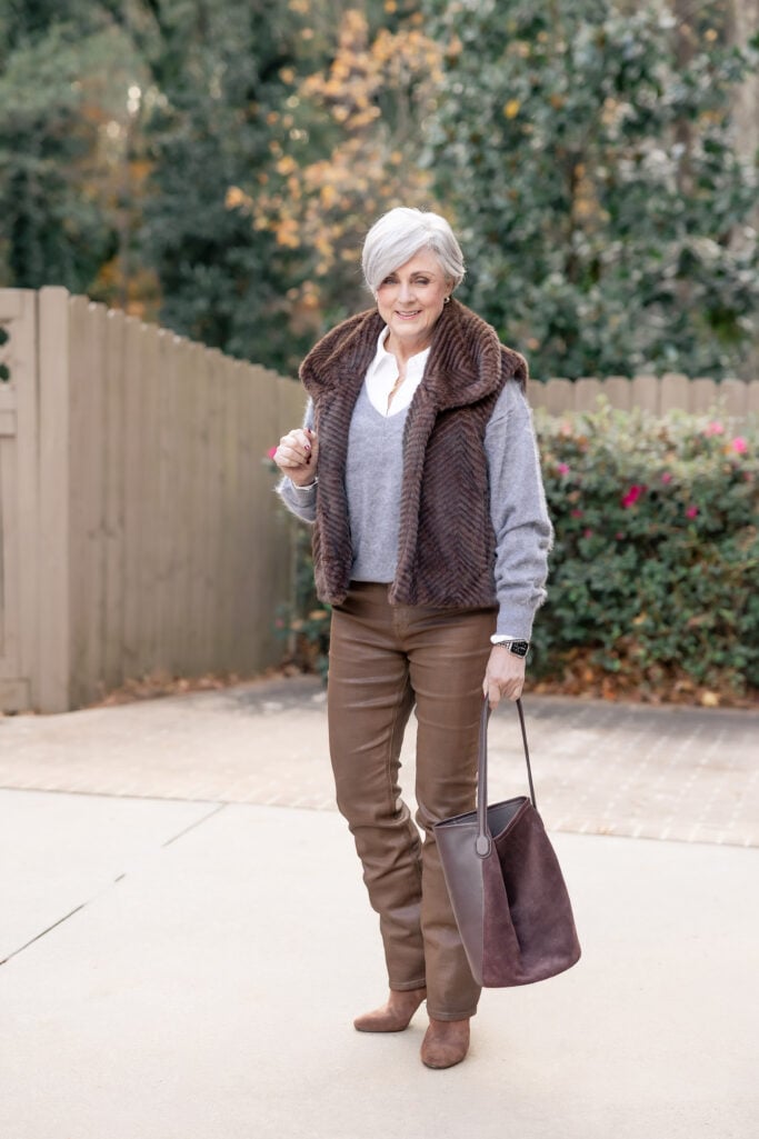 brown faux fur vest winter outfit for women over 50 with gray sweater and coated pants