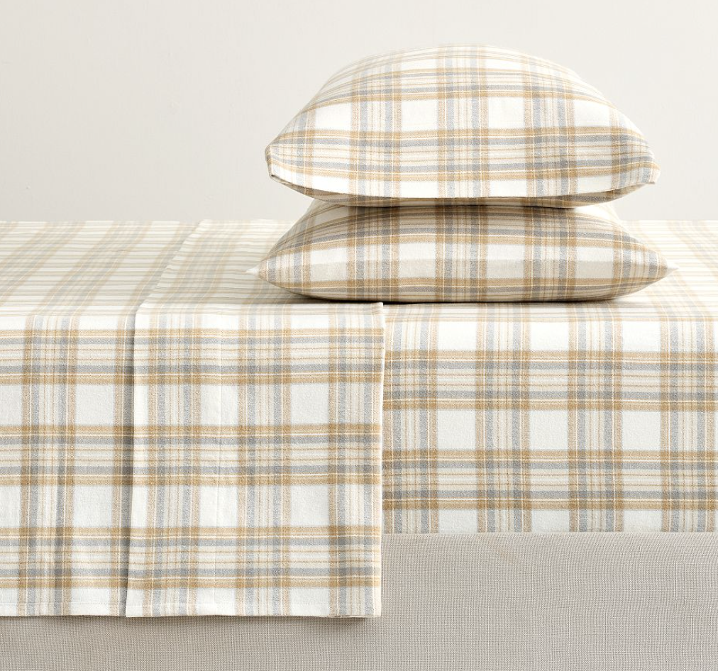 Pottery Barn Stewart Plaid Flannel Sheet Set in a neutral multicolored plaid, shown with two stacked matching pillowcases and folded sheet detailing the soft flannel texture.