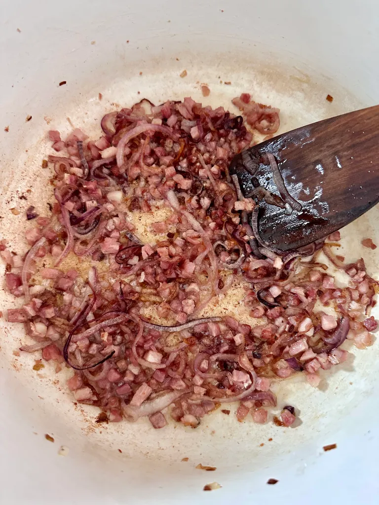 Browned pancetta and golden caramelized onions in white pot