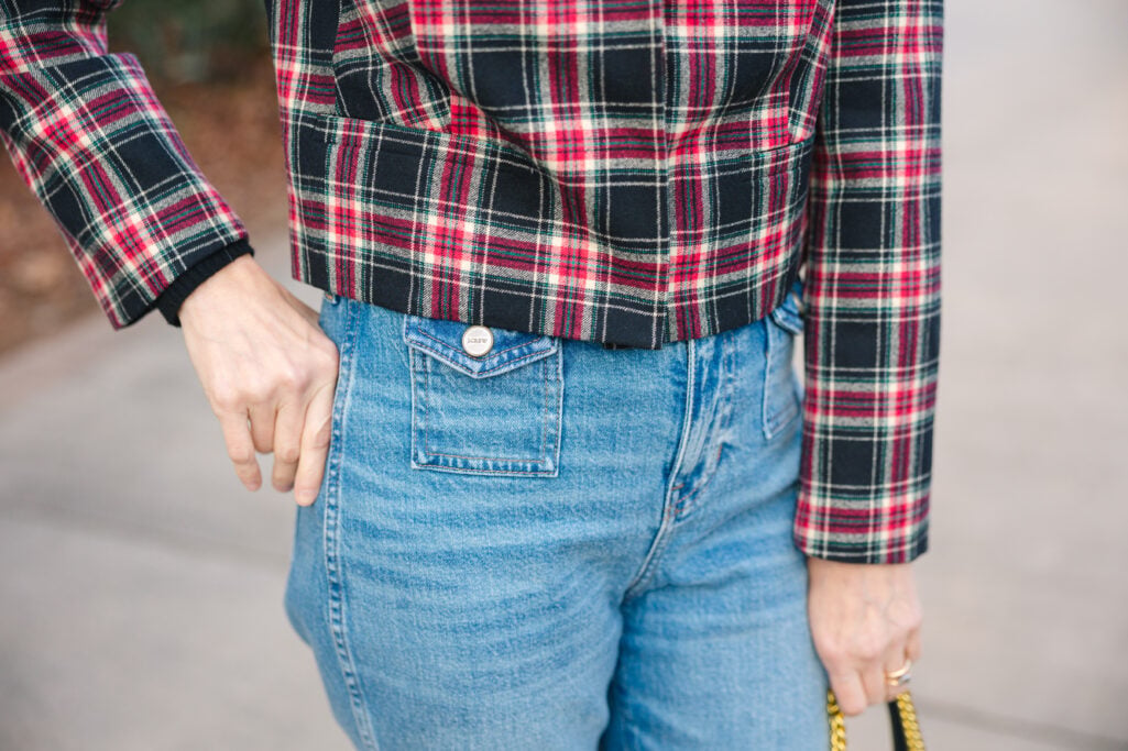 Detail shot of vintage flare jeans with patch pockets tucked into Stewart tartan jacket showing high-waisted fit for petite proportions