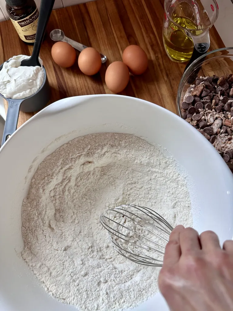 Whisking together cake mix and pudding mix in a white bowl