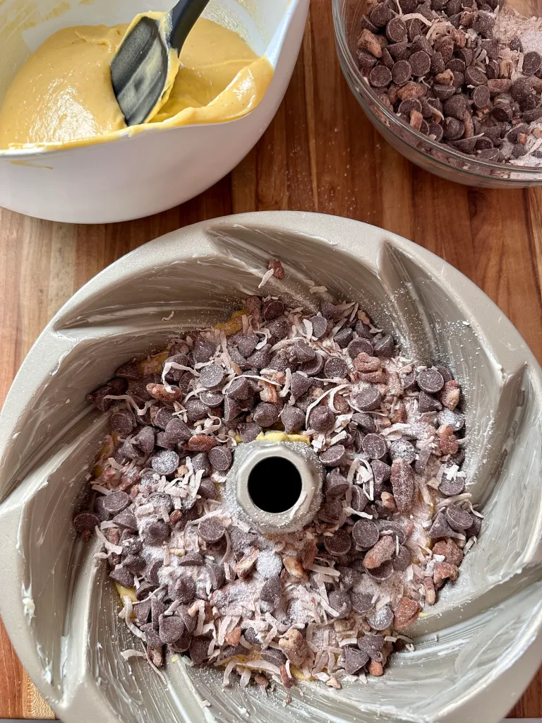 Sprinkling first layer of chocolate chip streusel over cake batter in bundt pan