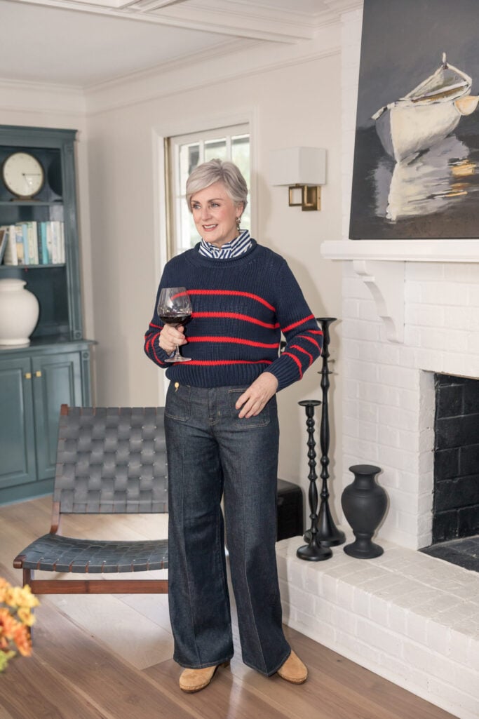 Beth in a navy and red striped sweater layered over a blue and white striped button-down shirt, with dark wide-leg jeans and tan suede clogs — how to wear stripes on stripes