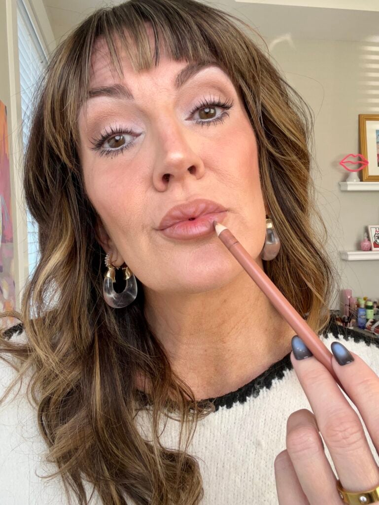 Woman applying nude pink Morphe lip liner in Honey shade to define lip shape, wearing soft luminous eye makeup with white inner corner highlight