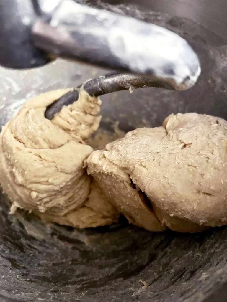 Smooth brioche dough wrapped around the dough hook after kneading
