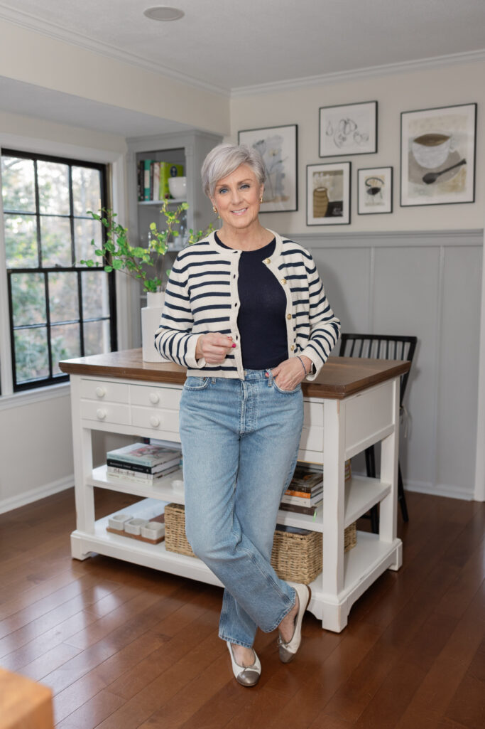 Beth Djalali in a navy and cream striped cardigan over a navy tee, paired with light wash straight-leg jeans and metallic silver ballet flats — classic grandmother style with a French twist.
