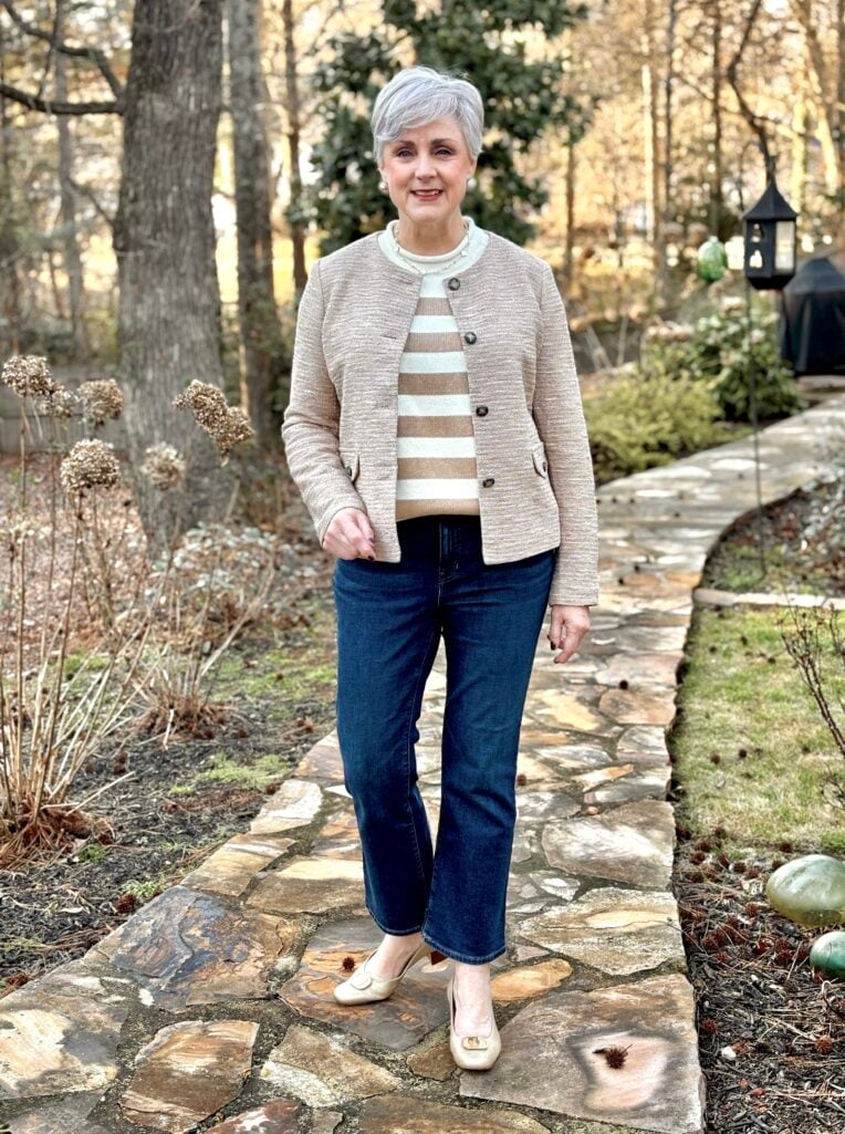 Beth Djalali wearing a camel tweed knit lady jacket with buttons over a camel and cream striped sweater and dark straight-leg jeans with cream ballet flats
