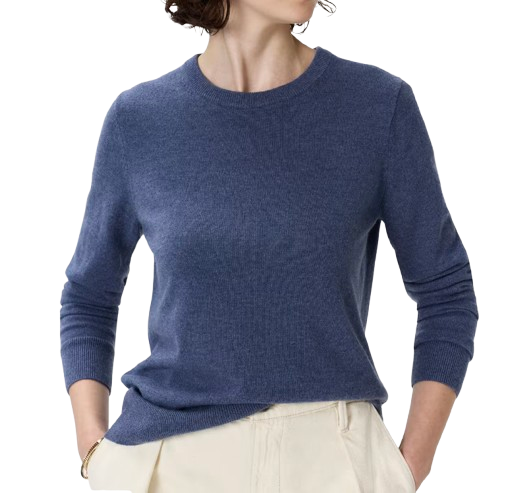 Model wearing a Quince Mongolian cashmere crew neck sweater in a soft blue shade, styled with light-colored trousers. Lightweight knit with a classic crew neckline and slim, polished fit.