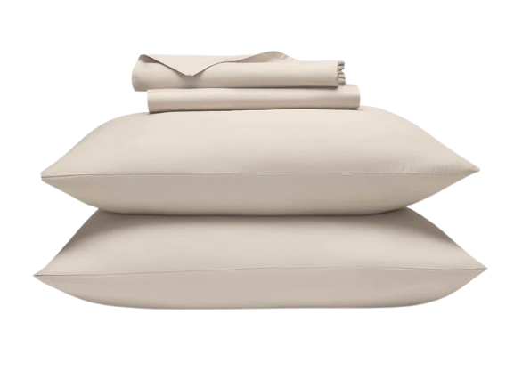 Cream-colored Brooklinen Luxe Sateen sheets neatly folded on a bed, showcasing smooth, wrinkle-resistant fabric with a subtle sheen.