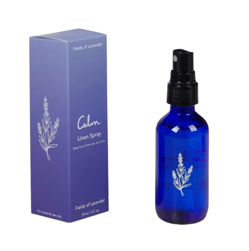 Lavender linen spray in a cobalt blue glass bottle with black spray top, shown beside a purple box labeled “Calm Linen Spray – Fields of Lavender.”