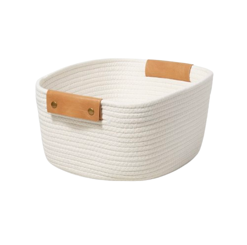 Oval cream rope storage basket with structured sides and tan leather handles secured with brass rivets.