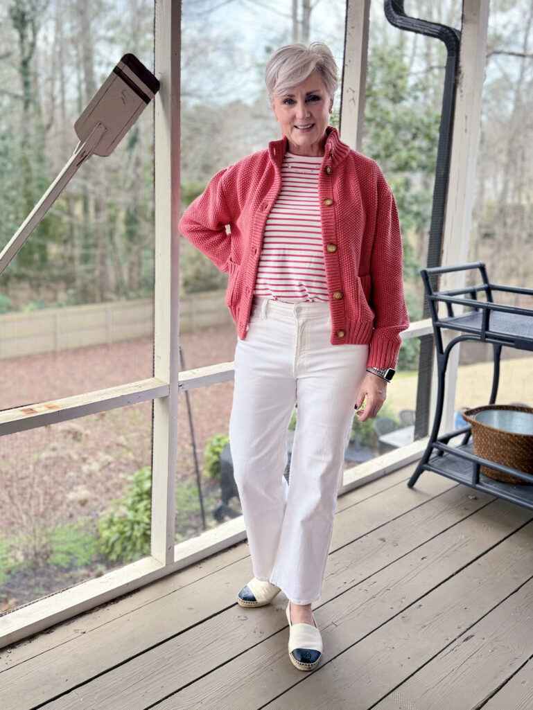 Beth wearing a coral Alice Walk Cotton Sweater Jacket over a pink and white striped crew tee, slim wide white denim, and colorblock espadrilles on the screened porch