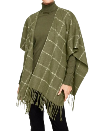 Olive green plaid ruana with windowpane pattern and fringe trim, styled over a coordinating green turtleneck and black pants.