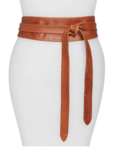 Cognac brown leather wrap belt tied in a knot at the waist, featuring a wide silhouette with long adjustable straps for a flattering, cinched look over dresses or sweaters.